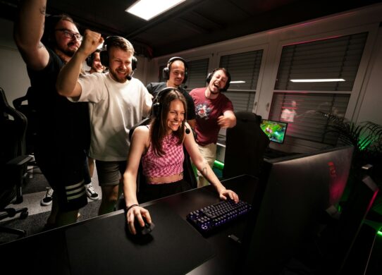 A group of people standing around a computer